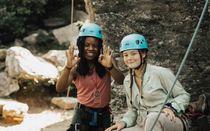 two students wearing rock climbing gear smile at the camera on an outward bound expedition in the blue ridge mountains